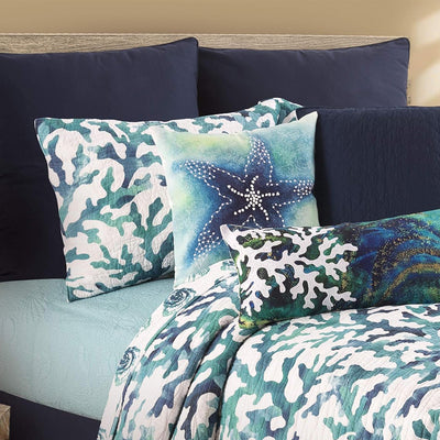 Es un cojín decorativo de estilo costero, con el diseño de una estrella de mar azul sobre un fondo que simula una acuarela en tonos azules y verdes.